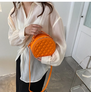 Detailed close-up of a vibrant orange round crossbody bag with quilted diamond stitching