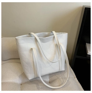 Detailed view of geometric triangle quilted pattern on a white faux leather tote bag