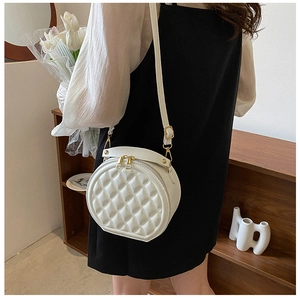 Detail of white quilted round crossbody bag with gold zippers and premium PU leather texture