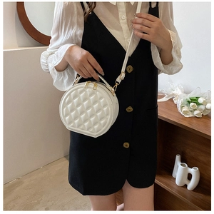 Detail of white round quilted shoulder bag with gold hardware and top handle design