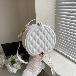 Close-up of a white quilted round shoulder bag with elegant gold zippers and top handle