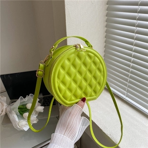 Close-up of bright green quilted round crossbody bag with golden metal zipper and top handle