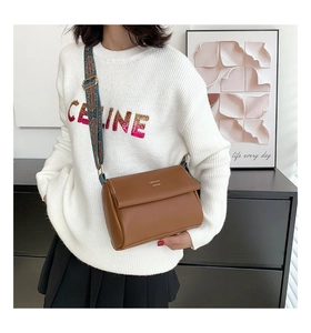 Détail d'un sac bandoulière marron avec une sangle au motif ethnique vintage