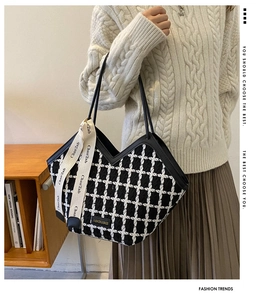 Detail of black and white plaid tote bag with ribbon decoration and leather handle