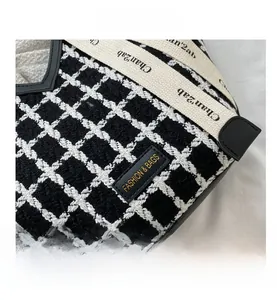 Close-up of black and white checkered tweed texture with leather fashion brand tag