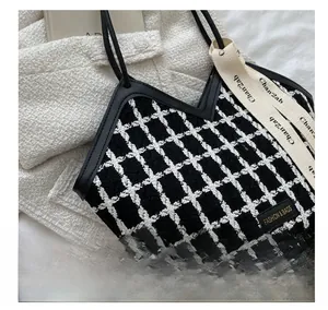 Close-up of black and white tweed pattern tote bag with leather straps and decorative ribbon
