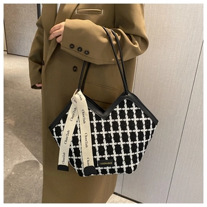 Close-up of black and white plaid tote bag featuring a leather strap and ribbon detail