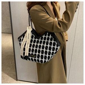 Detail of tweed checkered tote bag with V-shaped opening and decorative ribbon