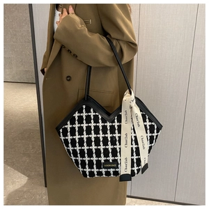 Detail of tweed checkered tote bag with decorative ribbon and fashion logo plaque