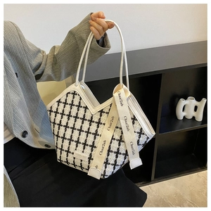 Detail of checkered tweed tote bag with leather trim and decorative scarf detail