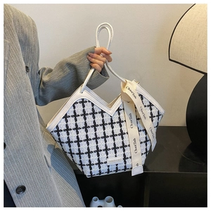 Close-up of checkered tweed tote bag with leather trim and silk ribbon on grey blazer