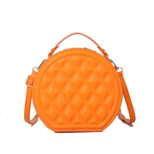 Orange quilted round crossbody bag with padded diamond stitching and gold metal hardware