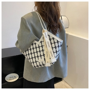 Detail of tweed checkered tote bag showing woven texture and decorative branding strap