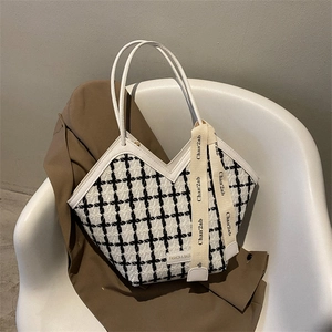 Detail of white tweed tote bag with black plaid patterns and silk ribbon decoration