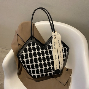 Fashionable black and white checkered tote bag with silk scarf on a white sofa chair