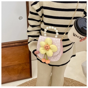 Détail du sac selle rose avec fleur 3D, poignée en perles et bandoulière dorée