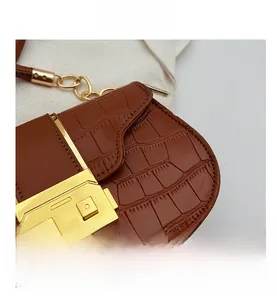 Détail d'un sac marron motif crocodile avec fermoir doré élégant et bandoulière chaîne