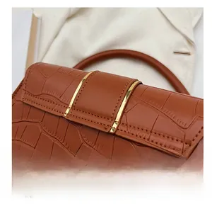 Détail du sac à bandoulière marron à motif crocodile avec coutures précises et bordure dorée
