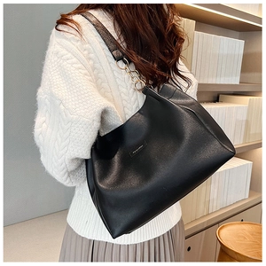 Dettaglio della borsa tote nera con catena d'oro e etichetta moda su maglia a coste