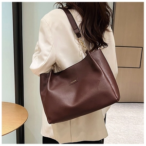 Vista dettagliata della borsa tote marrone scuro con catena dorata ed etichetta moda sulla spalla