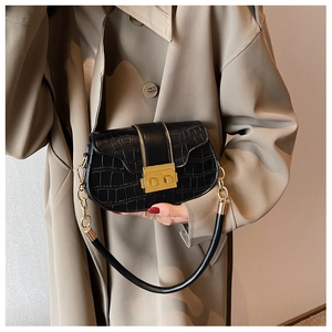 Détail du sac de selle noir façon crocodile avec un fermoir métallique rectangulaire doré