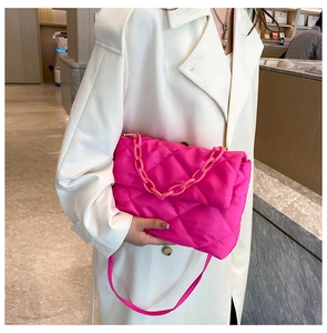 Gros plan sur un sac bandoulière matelassé rose vif avec grosse chaîne en plastique