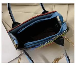 Detail view of ethnic style woven handbag interior with blue zipper and gold chain strap