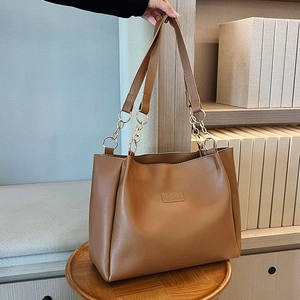 Dettaglio della borsa tote in pelle PU caramello con catena dorata e logo FASHION