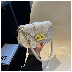 Gros plan sur un sac selle blanc motif crocodile en PU avec fermoir doré métallique