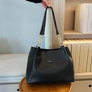 Dettaglio della borsa tote in pelle PU nera con manico a catena dorata e logo moda
