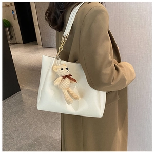 Detail of off-white tote bag with gold chain strap, SHION label and cute bear charm
