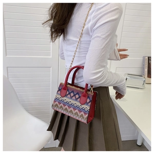 Detailed back view of a woman wearing the colorful woven ethnic handbag with a gold chain