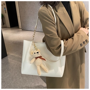 White large capacity tote bag with beige woven bear charm on a female model