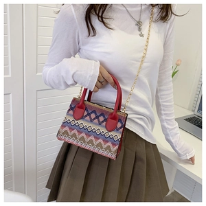 Detail view of Bohemian woven bag with colorful geometric patterns and red leather handles