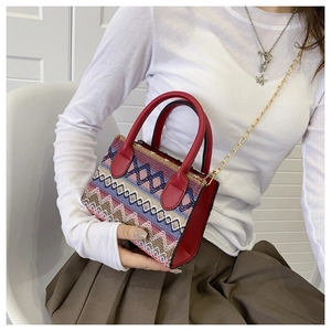 Detailed shot of ethnic embroidered handbag with red leather straps and gold chain
