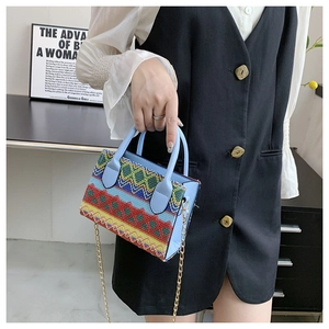 Detail view of ethnic style woven handbag with colorful patterns and light blue leather side