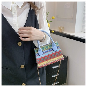 Detailed shot of multi-color woven ethnic handbag with blue handles and gold chain