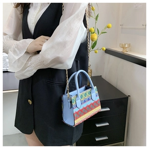 Close-up of ethnic geometric weave and light blue leather detail on a stylish crossbody bag