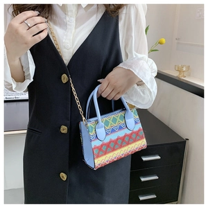 Detail of colorful ethnic embroidery and light blue leather on a small crossbody bag
