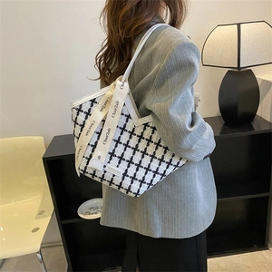 Chic black and white houndstooth tote bag with silk scarf detail shown on a model
