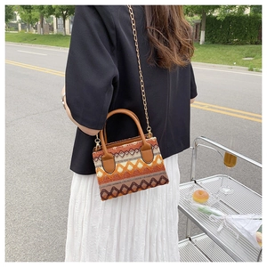 Close-up of bohemian woven handbag featuring orange geometric jacquard and gold chain