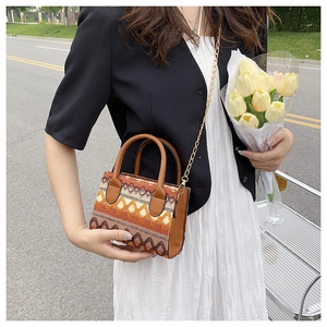 Detail of bohemian woven handbag with geometric patterns, chain strap and hand-held handle