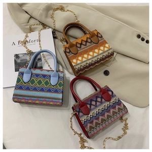 Ethnic knit shoulder bag with wavy patterns, leather handles and gold metal chains