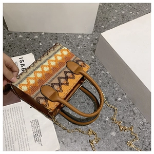 Detail of ethnic geometric woven pattern with brown leather handle and metal chain strap