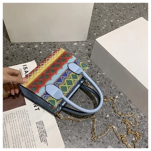Detail of bohemian woven handbag with colorful patterns and gold chain strap