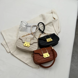 Trois sacs à main gaufrés crocodile en crème noir et marron sur blazer blanc