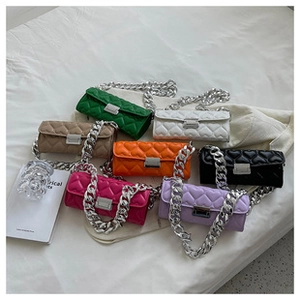 Flat lay of heart-quilted crossbody bags with silver chain straps in seven vibrant colors