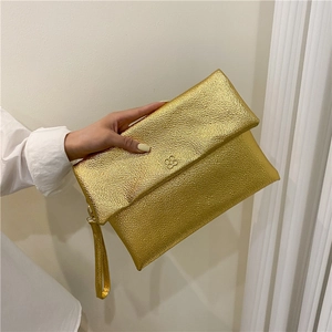 Elegant gold envelope clutch bag with textured metallic finish and clover ornament