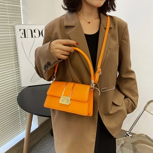 Fashionable orange leather bucket bag with gold clasp shown on a stylish model