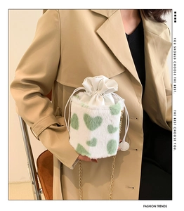 Detail of plush cow pattern bucket bag with green hearts and gold chain strap